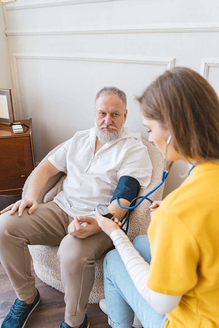 An elderly man having his blood pressure checked by a nurse during a routine health checkup indoors.